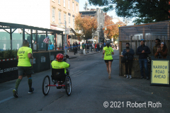 A wheelchair racer is accompanied by two guides from the Achilles Track club who help clear the way.