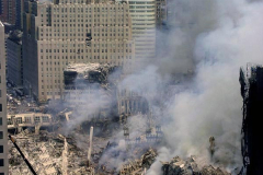The Empire State Building stands alone in the distance as the wreckage of the World Trade Center smolders. The collapse of the two 110-story towers creates a pile of more than one million tons of steel and debris that destroys neighboring buildings and covers Lower Manhattan in acrid dust and debris. The fires within the rubble burn for more than 3 months.
