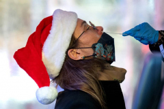 NEW YORK, NEW YORK - DECEMBER 23: Maia Goodell, from New York City, receives a COVID-19 test while wearing a Santa Claus hat the day before Christmas Eve in Times Square on December 23, 2021 in New York City. The holiday season was expected to resume with shows and events at full capacity but the COVID-19 variant omicron and the rise in cases across New York State has slowed reopening down. (Photo by Alexi Rosenfeld/Getty Images)