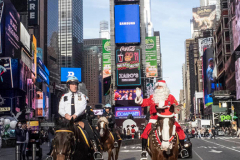 Santa Claus makes an early appearance in NYC as he rides thru Times Square not on a sled, but on horseback on an unseasonably warm 62 degree December day in Midtown Manhattan in NYC on 16 Dec 2021.