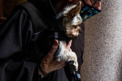 A Friar from the Church of St. Francis of Assisi in NYC stands with his little dog in hand awaiting visitors with their furry family for the Blessing of Animals that takes place every year on the first Sunday of October. 
In the Roman Catholic Church, St. Francis of Assisi is patron saint of animals, merchants and ecology.
People from all over bring their beloved furry and not so furry companions to receive blessings. This year broke an all time record of attendees who seek better horizons and better health for the upcoming year. (C) Bianca Otero, NYC. October 3, 2021.