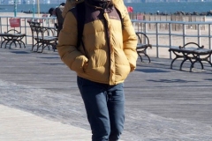 Coney Island Brooklyn. People stroll the Boardwalk in winter clothes on this sunny and cold day, 37 degrees some people sat on benches and others sunned themselves while The Coney Island Polar Bear Club jumped into the Atlantic Ocean for their weekly swim.