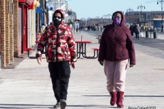Coney Island Brooklyn. People stroll the Boardwalk in winter clothes on this sunny and cold day, 37 degrees some people sat on benches and others sunned themselves while The Coney Island Polar Bear Club jumped into the Atlantic Ocean for their weekly swim.
