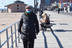 Coney Island Brooklyn. People stroll the Boardwalk in winter clothes on this sunny and cold day, 37 degrees some people sat on benches and others sunned themselves while The Coney Island Polar Bear Club jumped into the Atlantic Ocean for their weekly swim.