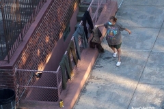 Covid19 Laundress: Woman hangs laundry on chain link fence leading to basement garage door during Covid Pandemic and heat wave   7/21/2020