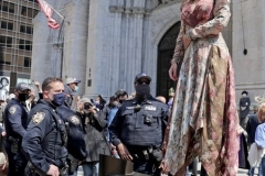 Participants march in the 2021 Annual Easter Bonnet Parade on Fifth Avenue in New York City on April 4, 2021. Paradegoers either dressed in their finest clothing or in colorful bonnets of all shapes and sizes still attended the annual Easter holiday tradition, on the steps of St. Patrick's Cathedral or in nearby Rockefeller Center, despite the Covid 19 pandemic. The New York City Police Department keeps a watchful eye on a paradegoer. (Photo by Andrew Schwartz)