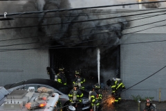 Firefighters work to gain entry during a five alarm fire at Logan;s Bus Company on Atlantic Avenue. (Photo by Lloyd Mitchell)