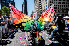 A man with large wings on a motorcycle at the New York City Pride March.