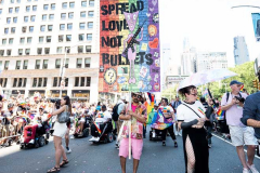 A man with a sign saying "Spread love not bullets" at the New York City Pride March.