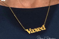 A close up of the necklace that NY State Governor Kathy Hochul wears that says "VAXED"