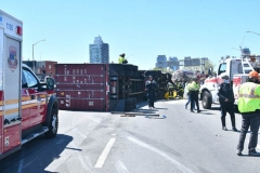 Cops, firefighters and big rig towers work to secure a tractor trailer that flipped over and sent 100's of gallons spilling onto the Brooklyn- Queens Expressway at Flushing Avenue.