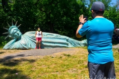 Artist Zaq Landsberg's sculpture entitled "Reclining Liberty" inside Morningside Park in New York City .The sculpture was created by Landsberg and features the Statue of Liberty posed on her side with her head propped up by her hand. The 25 foot long sculpture  is covered in oxidized copper paint and features a steel crown and was created using wood, foam and plaster resin.