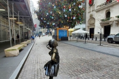 December 13,2020  Wall Street in front of the New York Stock Exchange residents and tourists visit the Fearless Girl statue and take photographs by the Stock exchange Christmas tree.