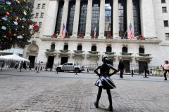 December 13,2020  Wall Street in front of the New York Stock Exchange residents and tourists visit the Fearless Girl statue and take photographs by the Stock exchange Christmas tree.