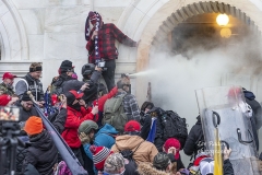 Washington, DC - January 6, 2021: Rioters use tear gas while clash with police trying to enter Capitol building through the front doors