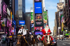 Santa Claus Rides A Horse Thru Times Square in NYC on an unseasonably warm 62 degree December day in Midtown Manhattan in NYC on 16 Dec 2021.