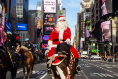 Santa Claus makes an early appearance in NYC as he rides thru Times Square not on a sled, but on horseback on an unseasonably warm 62 degree December day in Midtown Manhattan in NYC on 16 Dec 2021.