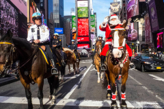 Santa Claus makes an early appearance in NYC as he rides thru Times Square not on a sled, but on horseback on an unseasonably warm 62 degree December day in Midtown Manhattan in NYC on 16 Dec 2021.