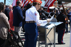 Street Naming
Lilac Court and Forest Avenue
Mariners Harbor
Staten Island, NY
April 22, 2022
Photographs by Mary DiBiase Blaich

The interaction of Lilac Court and Forest Avenue was renamed in a ceremony on Friday, April 22, 2022 for Nicholas M Troianiello, a World War II veteran of the Battle of Iwo Jima who served with the Marines.  Upon returning from service, he joined the FDNY and rose to the rank of Lieutenant, serving in Ladder 15 in Manhattan. He was a Purple Heart recipient.
At the ceremony, many groups gathered to honor Mr Troianiello including The Marine Corps League, the FDNY Retirees Association and current members of the FDNY.  Also in attendance were Congresswoman Nicole Malliotakis; Boro President Vito Fossella;  City Councilwoman Kamillah Hanks and two color guards: Marines 6th Communication Battalion and the FDNY Ceremonial Unit.  The Marine Corps League gave a 21 gun salute, and Frank Montella played Taps.  Carmella Montella needed a box to reach the microphone as she delivered the Invocation.