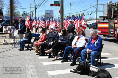 Street Naming
Lilac Court and Forest Avenue
Mariners Harbor
Staten Island, NY
April 22, 2022
Photographs by Mary DiBiase Blaich

The interaction of Lilac Court and Forest Avenue was renamed in a ceremony on Friday, April 22, 2022 for Nicholas M Troianiello, a World War II veteran of the Battle of Iwo Jima who served with the Marines.  Upon returning from service, he joined the FDNY and rose to the rank of Lieutenant, serving in Ladder 15 in Manhattan. He was a Purple Heart recipient.
At the ceremony, many groups gathered to honor Mr Troianiello including The Marine Corps League, the FDNY Retirees Association and current members of the FDNY.  Also in attendance were Congresswoman Nicole Malliotakis; Boro President Vito Fossella;  City Councilwoman Kamillah Hanks and two color guards: Marines 6th Communication Battalion and the FDNY Ceremonial Unit.  The Marine Corps League gave a 21 gun salute, and Frank Montella played Taps.  Carmella Montella needed a box to reach the microphone as she delivered the Invocation.