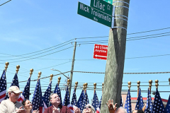 Street Naming
Lilac Court and Forest Avenue
Mariners Harbor
Staten Island, NY
April 22, 2022
Photographs by Mary DiBiase Blaich

The interaction of Lilac Court and Forest Avenue was renamed in a ceremony on Friday, April 22, 2022 for Nicholas M Troianiello, a World War II veteran of the Battle of Iwo Jima who served with the Marines.  Upon returning from service, he joined the FDNY and rose to the rank of Lieutenant, serving in Ladder 15 in Manhattan. He was a Purple Heart recipient.
At the ceremony, many groups gathered to honor Mr Troianiello including The Marine Corps League, the FDNY Retirees Association and current members of the FDNY.  Also in attendance were Congresswoman Nicole Malliotakis; Boro President Vito Fossella;  City Councilwoman Kamillah Hanks and two color guards: Marines 6th Communication Battalion and the FDNY Ceremonial Unit.  The Marine Corps League gave a 21 gun salute, and Frank Montella played Taps.  Carmella Montella needed a box to reach the microphone as she delivered the Invocation.