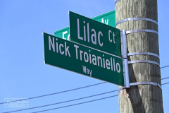 Street Naming
Lilac Court and Forest Avenue
Mariners Harbor
Staten Island, NY
April 22, 2022
Photographs by Mary DiBiase Blaich

The interaction of Lilac Court and Forest Avenue was renamed in a ceremony on Friday, April 22, 2022 for Nicholas M Troianiello, a World War II veteran of the Battle of Iwo Jima who served with the Marines.  Upon returning from service, he joined the FDNY and rose to the rank of Lieutenant, serving in Ladder 15 in Manhattan. He was a Purple Heart recipient.
At the ceremony, many groups gathered to honor Mr Troianiello including The Marine Corps League, the FDNY Retirees Association and current members of the FDNY.  Also in attendance were Congresswoman Nicole Malliotakis; Boro President Vito Fossella;  City Councilwoman Kamillah Hanks and two color guards: Marines 6th Communication Battalion and the FDNY Ceremonial Unit.  The Marine Corps League gave a 21 gun salute, and Frank Montella played Taps.  Carmella Montella needed a box to reach the microphone as she delivered the Invocation.