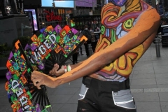New York City. "The Crossroads of the World" Times Square. Andy Golub Artist/Founder of Human Connection Arts paints 3 models in Times square, as onlookers watch and street performers and costume characters entertainvistors.