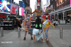 New York City. "The Crossroads of the World" Times Square. Andy Golub Artist/Founder of Human Connection Arts paints 3 models in Times square, as onlookers watch and street performers and costume characters entertainvistors.